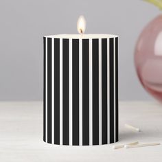 a black and white striped candle sits on a table