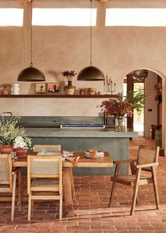 a dining room table with chairs and an oven in the back ground, surrounded by potted plants