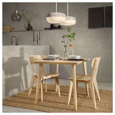 a wooden table with two chairs and a vase filled with flowers sitting on top of it