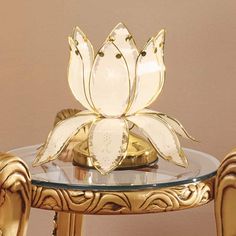 a glass and gold table with a flower shaped object sitting on it's top