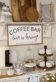 a coffee bar with cups and saucers on the top shelf, next to a sign that says love is brewing