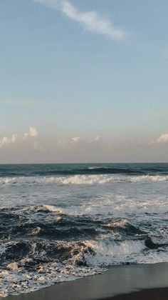 an ocean view with waves crashing on the shore and blue sky in the back ground