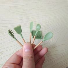 a person is holding several green spoons in their hand and they are on the table