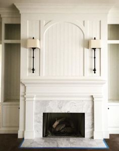 a white fireplace with two lamps on either side