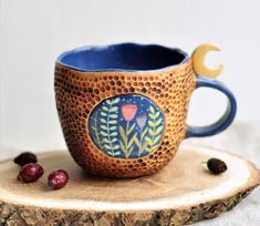 a ceramic cup sitting on top of a piece of wood next to cranberries