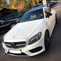 a white car parked in a parking lot next to other cars on the side of the road