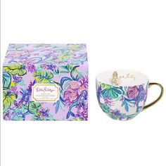 a cup and box sitting next to each other in front of a white background with purple flowers on it