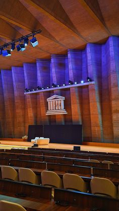 an empty auditorium with rows of seats in front of the stage and columns on the wall