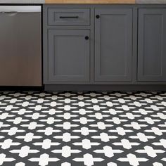 a black and white tiled floor in a kitchen with sink, dishwasher and cabinets