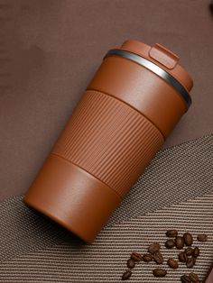 a coffee cup sitting on top of a table next to some coffee beans and a cell phone