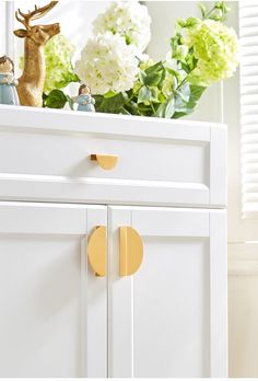 a close up of a dresser with flowers in the background and a deer figurine on top