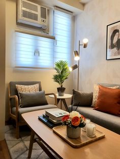 a living room filled with furniture and a coffee table in front of an air conditioner