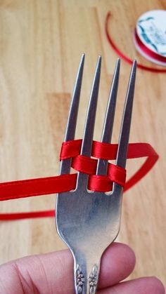 a hand holding a fork with red ribbon on it