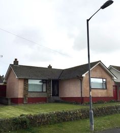 a house that is next to a street light on a pole in front of some grass