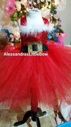 a red and white santa claus tutule dress sitting in front of a christmas tree