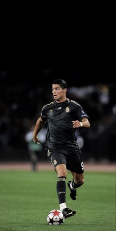 a soccer player is running with the ball in his hand while wearing black and gold