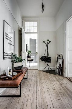 a white room with wooden floors and pictures on the wall, along with a bench