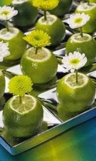 limes and daisies are arranged in small squares on a silver tray with mirrored surface