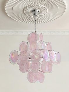 a pink chandelier hanging from the ceiling in a room with white walls and ceilings