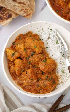 two bowls filled with rice and chicken curry next to pita bread on a table