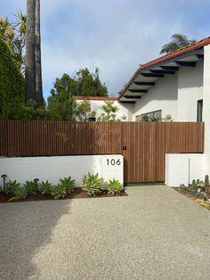 a white house with a wooden fence and numbers on the front door is seen in this image