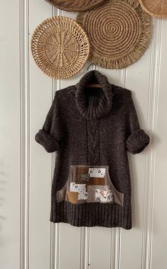 a brown sweater hanging on the wall next to wicker baskets