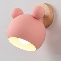 a pink light that is on the wall next to a mouse head shaped light fixture