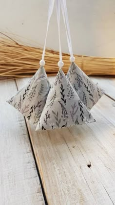 three paper flowers hanging from strings on a wooden surface with white string attached to them