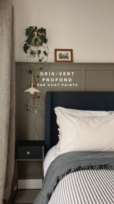 a bedroom with a bed, nightstand and plant hanging on the wall next to it