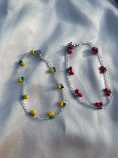 two beaded necklaces are laying on a white sheet