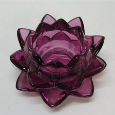 a purple glass flower sitting on top of a white table