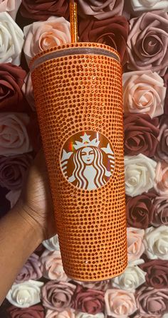 the starbucks cup is made out of orange mesh and has a gold straw in it