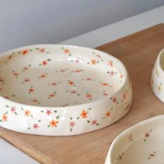 three white bowls sitting on top of a wooden cutting board next to eachother