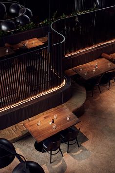 an overhead view of a restaurant with wooden tables and black chairs, along with metal railings