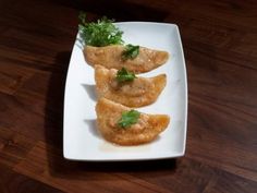 three pieces of food on a white plate with green garnish and parsley