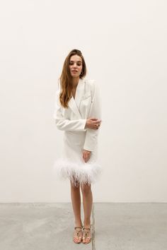 This elegant white suit is perfect for making a statement at a Christmas party or formal event. The minimalist design features a jacket and skirt set crafted from a cotton blend, offering both comfort and a sharp, polished look. The standout detail is the soft, luxurious feathers along the hem of the skirt, adding a playful and chic twist to the classic silhouette. Its sleek and understated style makes it not only suitable for office wear but also an ideal bridal suit for modern, non-traditional Suit With Feathers, Party Suit For Women, Suit Dress Wedding, Cotton Office Wear, White Suit Dress, Feather Suit, Wedding Guest Suit, Bridal Shower White, Formal Suits For Women