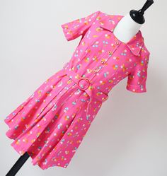 SUPER CUTE! Perfectly formed 1970's summer mini-dress in bright bubblegum pink cotton patterned with daisies and blue cherries. The cotton is a dense high quality and the colours are crisp. Details include the semi-pleated skirt, decorative button trim and matching buckle belt. The old vintage size label says '38' but in my opinion the fit is much smaller and like an XXS / XS or a UK 6 / 8 We advise that you check all the measurements below. The garment is mid-weight and is lined. Excellent Cond Pink Retro Print Summer Dress, Cotton Dresses With Retro Print For Summer, Pink Casual Dress With Retro Print, Casual Pink Dress With Retro Print, Vintage Pink Mini Length Dress, Retro Pink A-line Dress, Fitted Pink Cotton Dress, Cotton Short Sleeve Dresses With Retro Print, Short Sleeve Cotton Dress With Retro Print