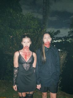 two people with blood on their faces standing next to each other in front of trees