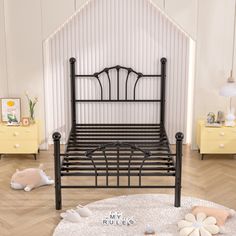 a black metal bed frame sitting on top of a wooden floor next to yellow dressers