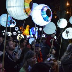 a large group of people standing around with paper lanterns in the shape of eyeballs