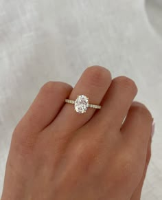 a woman's hand with a diamond ring on top of her finger and the other hand holding an engagement ring