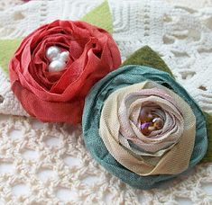 two fabric flowers sitting on top of a blanket