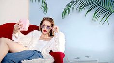 a woman sitting in a red chair holding a pink object