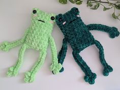 two crocheted stuffed animals sitting next to each other on a white surface with plants in the background