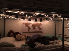 there is a world map on the wall above the bed in this dorm room with teddy bears