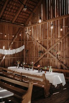 a wooden barn with tables and white tablecloths