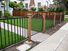 an iron fence with wooden posts in front of a house