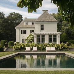 a large white house sitting next to a pool in front of a lush green field