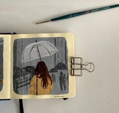 an open notebook with a drawing of a girl holding an umbrella and two people walking in the rain