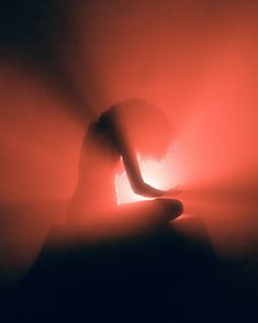 a person sitting in the fog with their hands on their knees